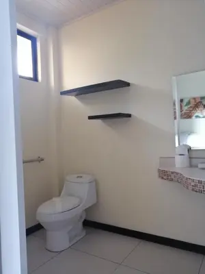 a bathroom with a white toilet and a sink at Cabinas Gosen in Puntarenas
