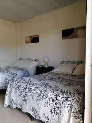 a bedroom with two beds and a table with a lamp at Cabinas Gosen in Puntarenas