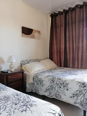 a bedroom with two beds and a table with a lamp at Cabinas Gosen in Puntarenas