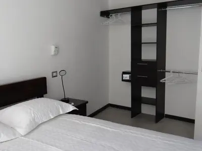 a bedroom with a bed and a black book shelf at Maria´s Apartments in Alajuela City