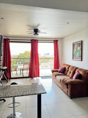 a living room with a couch and red curtains at Maria´s Apartments in Alajuela City