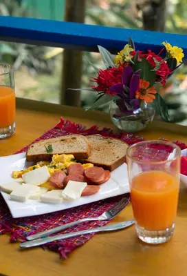 a plate of food with bread and cheese and orange juice at Agutipaca Bungalows in Bagaces