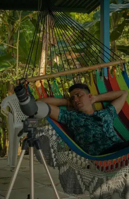 a man laying in a hammock with a camera at Agutipaca Bungalows in Bagaces