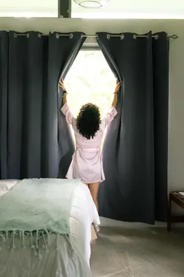 a woman in a pink dress is opening a window at Agutipaca Bungalows in Bagaces