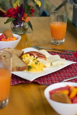 a table with a plate of breakfast food and orange juice at Agutipaca Bungalows in Bagaces