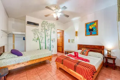 a bedroom with two beds and a ceiling fan at Hotel Tropical Sands Dominical in Dominical