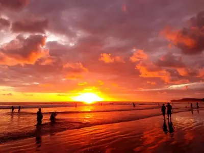 a group of people standing on a beach at sunset at Hotel Tropical Sands Dominical in Dominical
