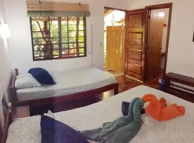a bedroom with two beds and a room with a window at Hotel Tropical Sands Dominical in Dominical