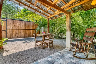 a patio with a table and chairs under a wooden pergola at Hotel Villas Tangerine in Sámara