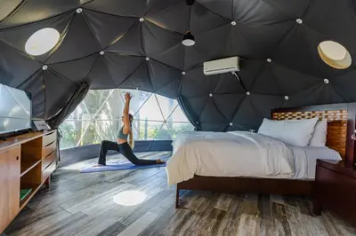 a woman is doing yoga in a tent at Chira Glamping Resort Monteverde in Monteverde Costa Rica