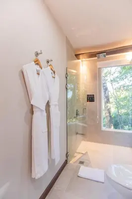 a bathroom with a shower and a white robe hanging on a wall at Chira Glamping Resort Monteverde in Monteverde Costa Rica