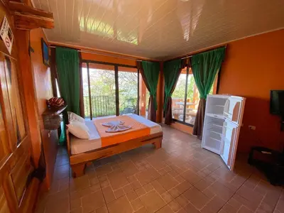a bedroom with a bed and a refrigerator and windows at Valle Encantado in San Isidro