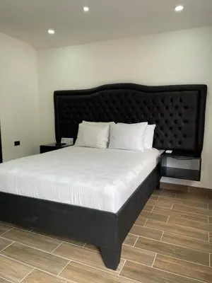 a large bed with a black headboard and white pillows at Cabinas Vista Al Golffo in Monteverde Costa Rica