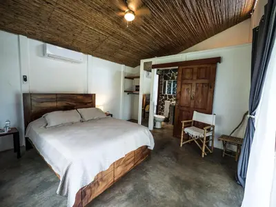 a bedroom with a large bed and a chair at Hotel Peace & Lodge in Sámara