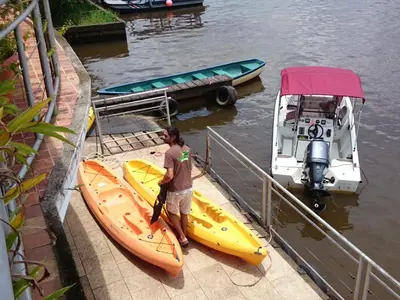 a man is loading two kayaks onto a boat at Tortuguero Adventures GuestHouse in Tortuguero