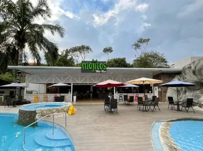 a hotel with two pools and chairs and umbrellas at Hotel PZ Country Club & Conference Center in San Isidro