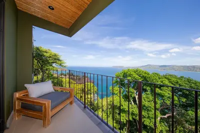 a balcony with a bench and a view of the ocean at 360 Splendor Del Pacifico Residences in Playa Flamingo