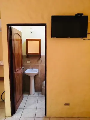 a bathroom with a toilet and a television on a wall at Hotel Casa Esmeralda in Sámara