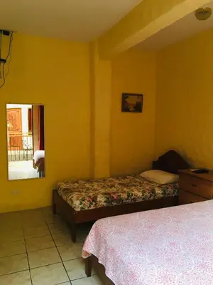a hotel room with two beds and a mirror at Hotel Casa Esmeralda in Sámara