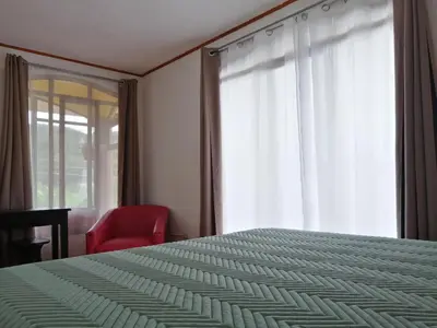 a bedroom with a bed and a red chair and a window at Hotel Santa Fe B&B in Monteverde Costa Rica