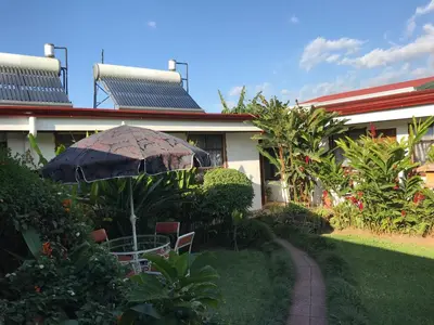 a patio with an umbrella and chairs in front of a house at Casa Kibi Kibi in San José