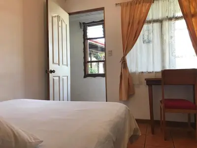 a bedroom with a bed and a window and a chair at Casa Kibi Kibi in San José