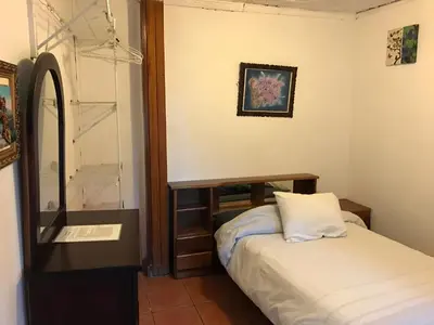 a small bedroom with a bed and a mirror at Casa Kibi Kibi in San José