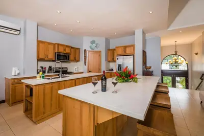 a kitchen with wooden cabinets and a counter with two wine glasses at Beachfront Potrero - nice 7-BR villa, private cook included - Casa Royal in Potrero