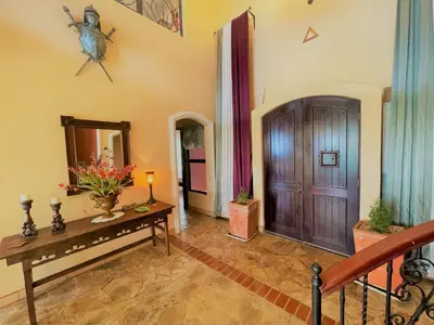 a living room with a table and a wooden door at Playa Potrero, Oceanview Villa Oasis with salt-water pool for up to 8 people in Potrero