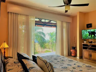 a bedroom with a bed and a large window at Playa Potrero, Oceanview Villa Oasis with salt-water pool for up to 8 people in Potrero