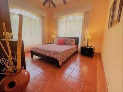 a bedroom with a bed and two windows at Playa Potrero, Oceanview Villa Oasis with salt-water pool for up to 8 people in Potrero