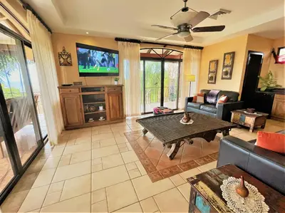a living room with a couch and a tv at Playa Potrero, Oceanview Villa Oasis with salt-water pool for up to 8 people in Potrero