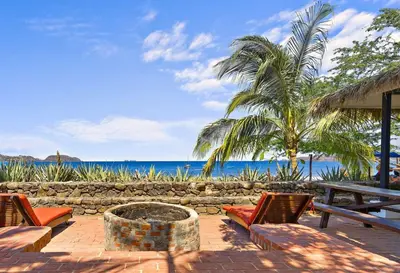 a patio with chairs and a table and a palm tree at Playa Potrero - beachfront Villa, big private pool - Casa Bella Catalina in Potrero
