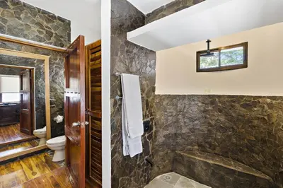 two images of a bathroom with a stone wall at Playa Potrero - beachfront Villa, big private pool - Casa Bella Catalina in Potrero
