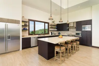 a kitchen with a large island with bar stools at Casa Symbiotica - Exclusive Villa with Gym, Infinity Pool & Housekeeping in Brasilito