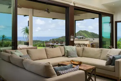 a living room with a large couch and large windows at Casa Symbiotica - Exclusive Villa with Gym, Infinity Pool & Housekeeping in Brasilito