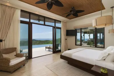 a bedroom with a bed and a view of the ocean at Casa Symbiotica - Exclusive Villa with Gym, Infinity Pool & Housekeeping in Brasilito