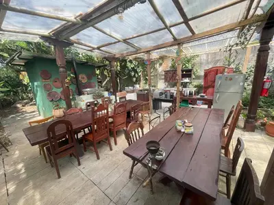 a patio with wooden tables and chairs and an outdoor kitchen at Kakao Lodge & Garden Río Celeste in Bijagua