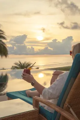 a woman sitting in a chair with a drink at Hotel Boutique Lagarta Lodge in Nosara
