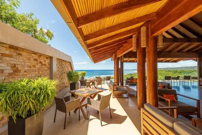 an outdoor patio with tables and chairs and the ocean at Hotel Boutique Lagarta Lodge in Nosara