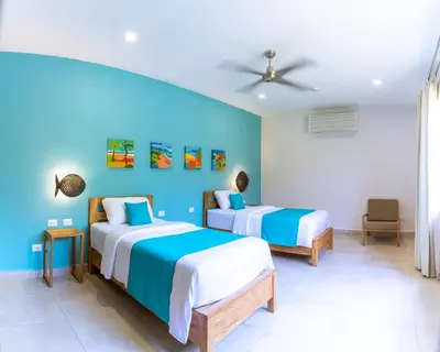 two beds in a room with blue walls at Hotel Boutique Lagarta Lodge in Nosara