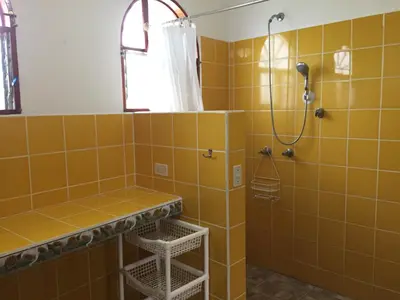 a bathroom with a shower with yellow tiles at La Perlita in Jacó