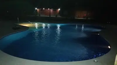 a large blue swimming pool at night at Cabañas San Isidro in Ángeles