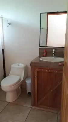 a bathroom with a toilet and a sink and a mirror at Cabañas San Isidro in Ángeles