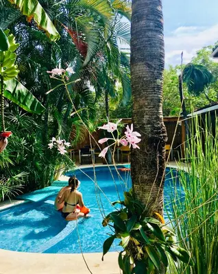 a woman sitting in a pool next to a palm tree at Ten North Tamarindo Beach Hotel in Tamarindo