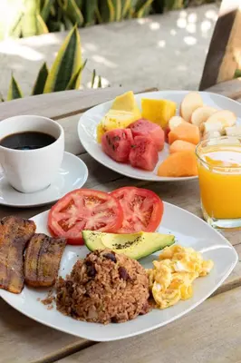 a table with two plates of breakfast food and a cup of coffee at Hotel Villa Hermosa in Liberia