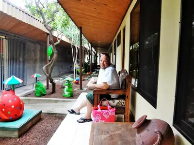 a man sitting on a bench outside a house at Hotel Villa Hermosa in Liberia