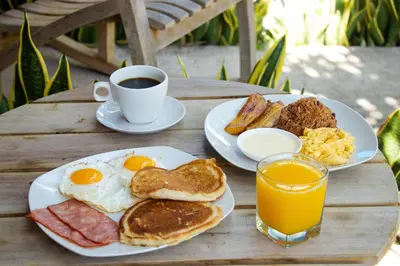a table with two plates of breakfast foods and a cup of coffee at Hotel Villa Hermosa in Liberia