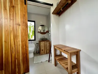 a bathroom with a toilet and a wooden door at Almendros Eco-Villas in Fortuna