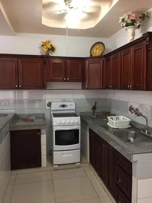 a kitchen with wooden cabinets and a white stove top oven at Casa Playa Bahia Ballena de Osa in Uvita